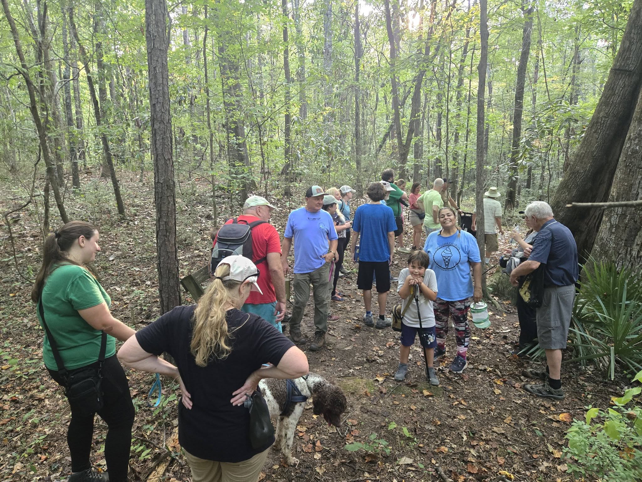 A group of adults and children enjoying a wooded hiking trail together